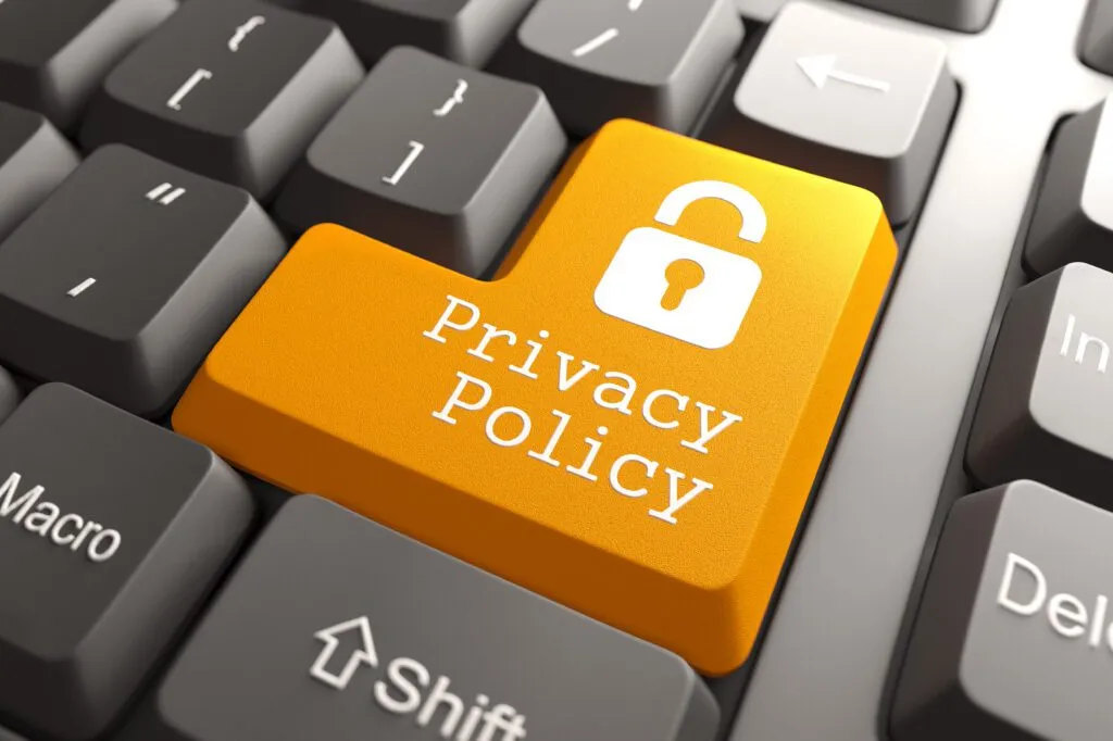 Klawiatura komputerowa z wyróżnionym pomarańczowym klawiszem „Privacy Policy”, symbolizującym ochronę danych i politykę prywatności online.